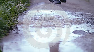 Puddle Jump: Boy's Playful Splash in Rubber Boots on a Gloomy Day, Slow Motion Sprays