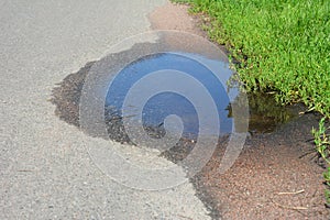 Puddle photo. Pot hole or pothole image of a broken cracked asphalt pavement with a dirty water puddle as a transportation symbol