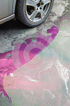 puddle of pink coolant and brown technical liquids on the concrete floor near car