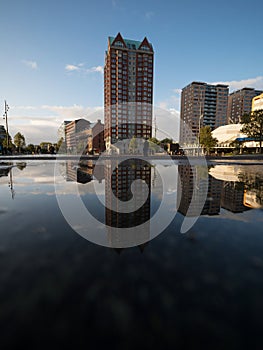 Puddle pond mirror reflection of modern architecture building skyscraper Blaak central square in Rotterdam Netherlands