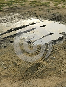 Puddles in rainy day. Muddy field, dirt road after rain. Puddle and mud with tire track texture. Impassibility Of Roads.