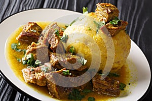 Puerto Rican Mofongo made from plantains, garlic and chicharron served with meat and broth close-up. horizontal