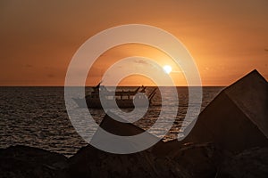 PUERTO RICO, SPAIN. Amazing sunset, rocks and stones at foreground and glass  bottom boat passing