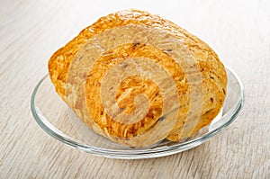 Puff bun in transparent saucer on wooden table