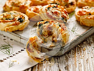 Puff Pastry appetizers Pinwheels stuffed with salmon, cheese and spinach on wooden board