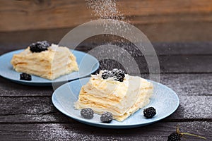 puff pastry with blackberries sprinkled with powdered sugar on a wooden background