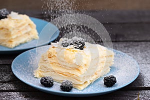 puff pastry with blackberries sprinkled with powdered sugar on a wooden background