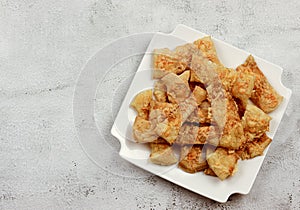 Puff pastry cheese straws on a white rectangular plate on a light gray background.