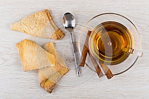 Puff pastry, cup of tea, cinnamon sticks on saucer, spoon