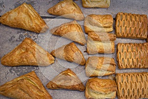 Puff pastry rolls. fresh sweet baking on papyrine. Several kinds of crispy pies lie in rows on a baking sheet on the counter. Top photo