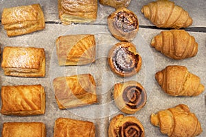 Puff pastry rolls. fresh sweet baking on papyrine. Several kinds of crispy pies lie in rows on a baking sheet on the counter. Top