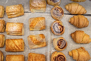 Puff pastry rolls. fresh sweet baking on papyrine. Several kinds of crispy pies lie in rows on a baking sheet on the counter. Top photo