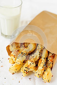 Puff Pastry Sticks in a Paper Bag with a Glass of Milk, copy space for your text