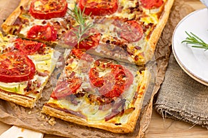 Puff pastry tart pizza style with tomatoes, courgette, and bacon