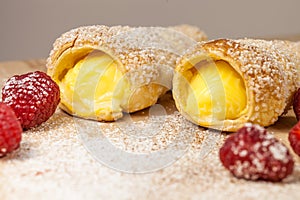Puff pastry vanilla horns and raspberries on a wooden board