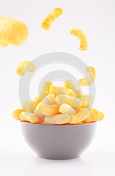 Puffed corn chips in gray bowl on white background