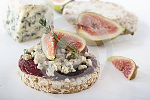 Puffed exploded wheat grains with slices of figs and blue cheese on a thin layer of jam