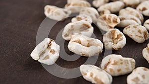 Puffed spelt wheat on a dark wooden background. Uncooked cereal.