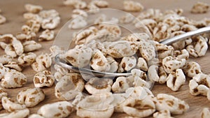 Puffed spelt wheat in a metal spoon close up. Uncooked raw flakes