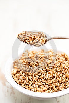 Puffed spelt in white bowl on wooden background