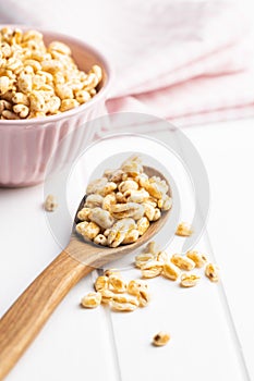 Puffed wheat covered with honey in wooden spoon