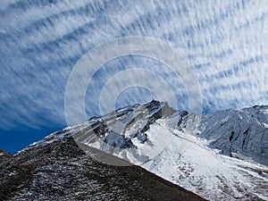 Puffy mountains under feathery clouds