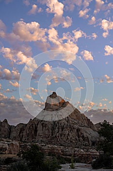 Puffy White Clouds Waft Over Rocks in Desert at Sunrise