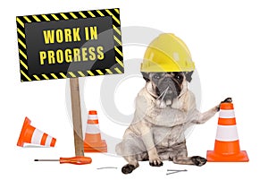 Pug dog with constructor safety helmet and yellow and black work in progress sign on wooden pole