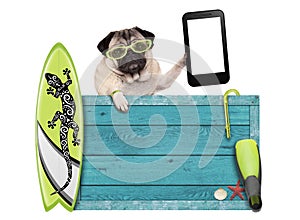 Pug dog on vacation with blue vintage wooden beach sign, surfboard and mobile phone / tablet, isolated on white background