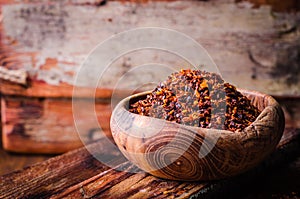 Pul biber - crushed red chili pepper in vintage bowl on wooden background. Selective focus. Toned image. Turkish cuisine photo