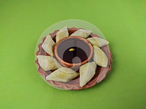 puli pithe or bengali rice flour dumplings with coconut fillings served on a clay plate with jaggery. this traditional dish made