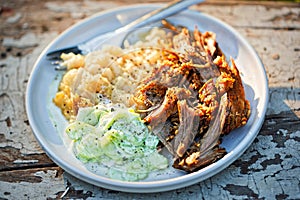 Pulled, seasoned pork, with mashed fried potatoes and cucumber and sour cream salad photo