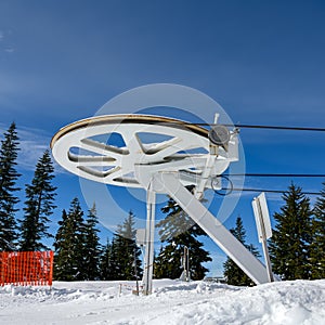 Pulley wheel from the top of a ski lift with a blue sky background