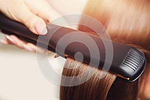 Pulling strands of hair with professional ultrasonic iron tool. Spa care.