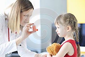 Pulmonologist doctor holding hormonal inhaler in front of little girl