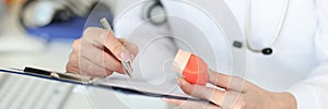 Pulmonologist holding inhaler in hands and writing in documents closeup