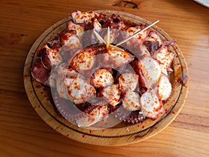 Pulpo a la gallega in Spanish meaning Galician-style octopus served on the wooden plate