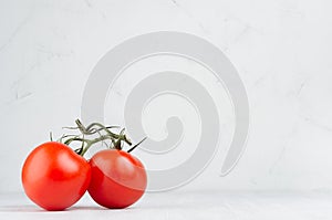 Pulpy red tomatoes on branch in light soft white modern kitchen interior with copy space.