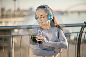 Fit girl in grey sportswear fattaching the pulsometer on her arm photo