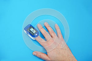 Pulse oximeter, finger digital device to measure oxygen saturation in blood on blue background