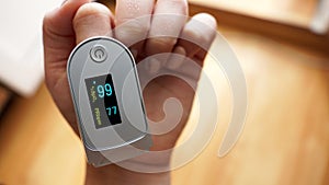 Pulse oximeter on finger showing oxygen saturation and heart rate