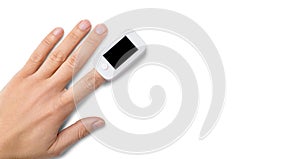 Pulse oximeter on finger on white background top view copy space