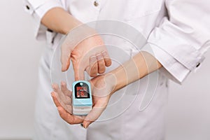 Pulse oximeter with hand of doctor isolated on white. Measuring oxygen saturation, pulse rate and oxygen levels. The