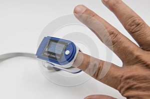 Pulse oximeter in a male patient`s fingertip on white background