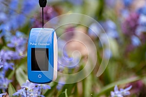 Pulse oximeter outdoors close-up in blue flowers