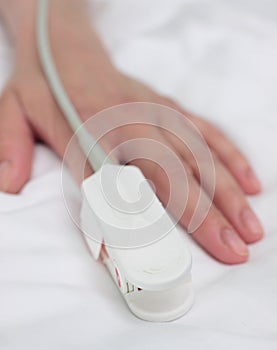 Pulse oximeter on the patient's hand. Medical background.