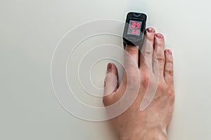 Pulse oximeter is placed on the index finger of a manâ€™s hand to measure saturation. Close-up