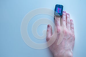 Pulse oximeter is placed on the index finger of a manâ€™s hand to measure saturation. Close-up