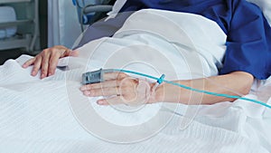 Pulse oximeter on senior patient`s hand at hospital