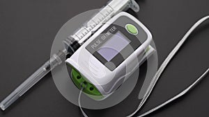 Pulse Oximeter with syringe. Monitor showing saturation of oxygen in the blood and pulse rate of patient. Close up